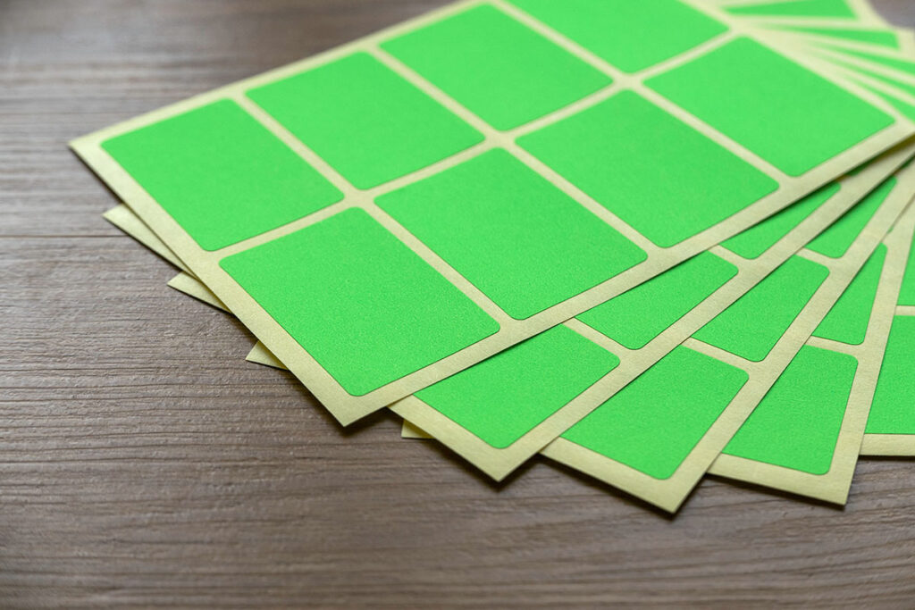 A set of green paper sticker labels sits against a wooden background.