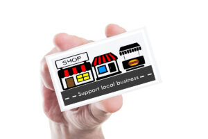 A person holding a card featuring illustrations of shops and the text "Support local business."
