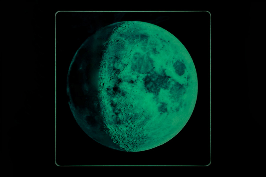 A glowing representation of the moon in a dark setting, showcasing detailed lunar craters and surface textures, with a greenish hue.